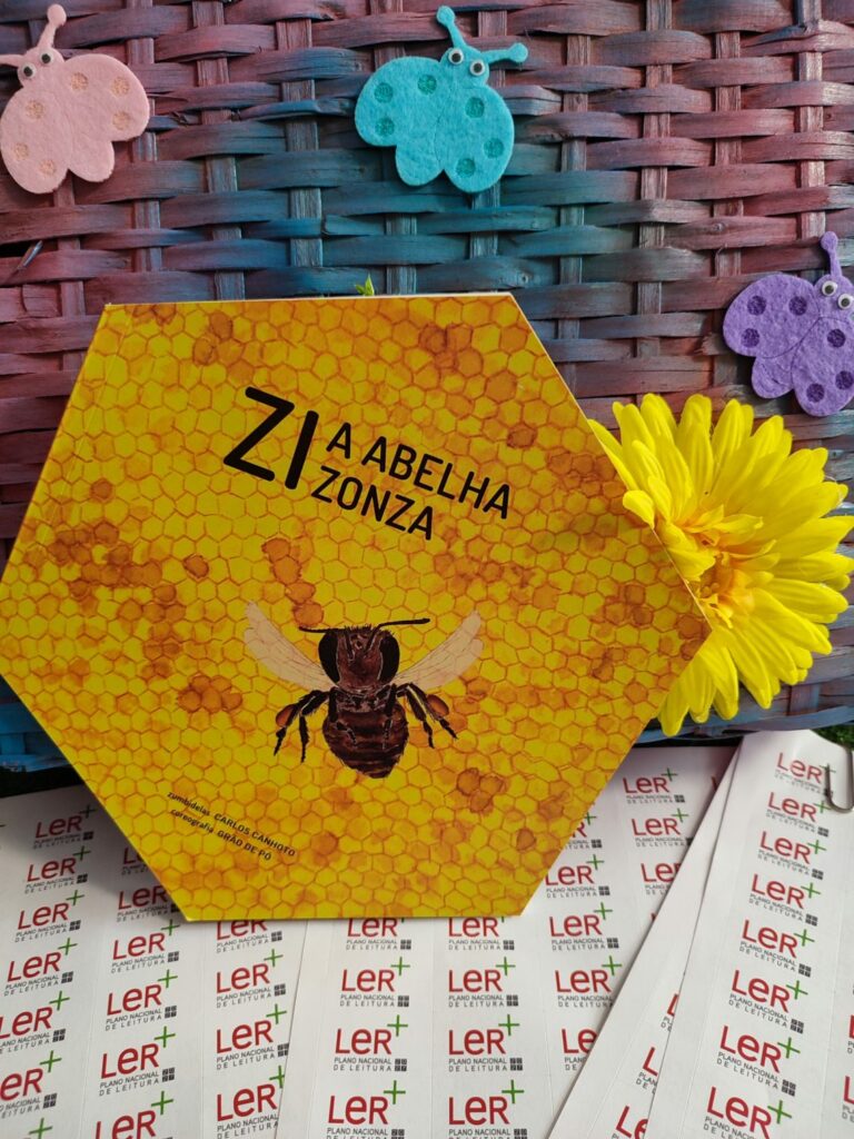 Exemplar de «Zi, a abelha zonza», livro ilustrado de Carlos Canhoto e grão de pó, com autocolantes do Plano Nacional de Leitura
