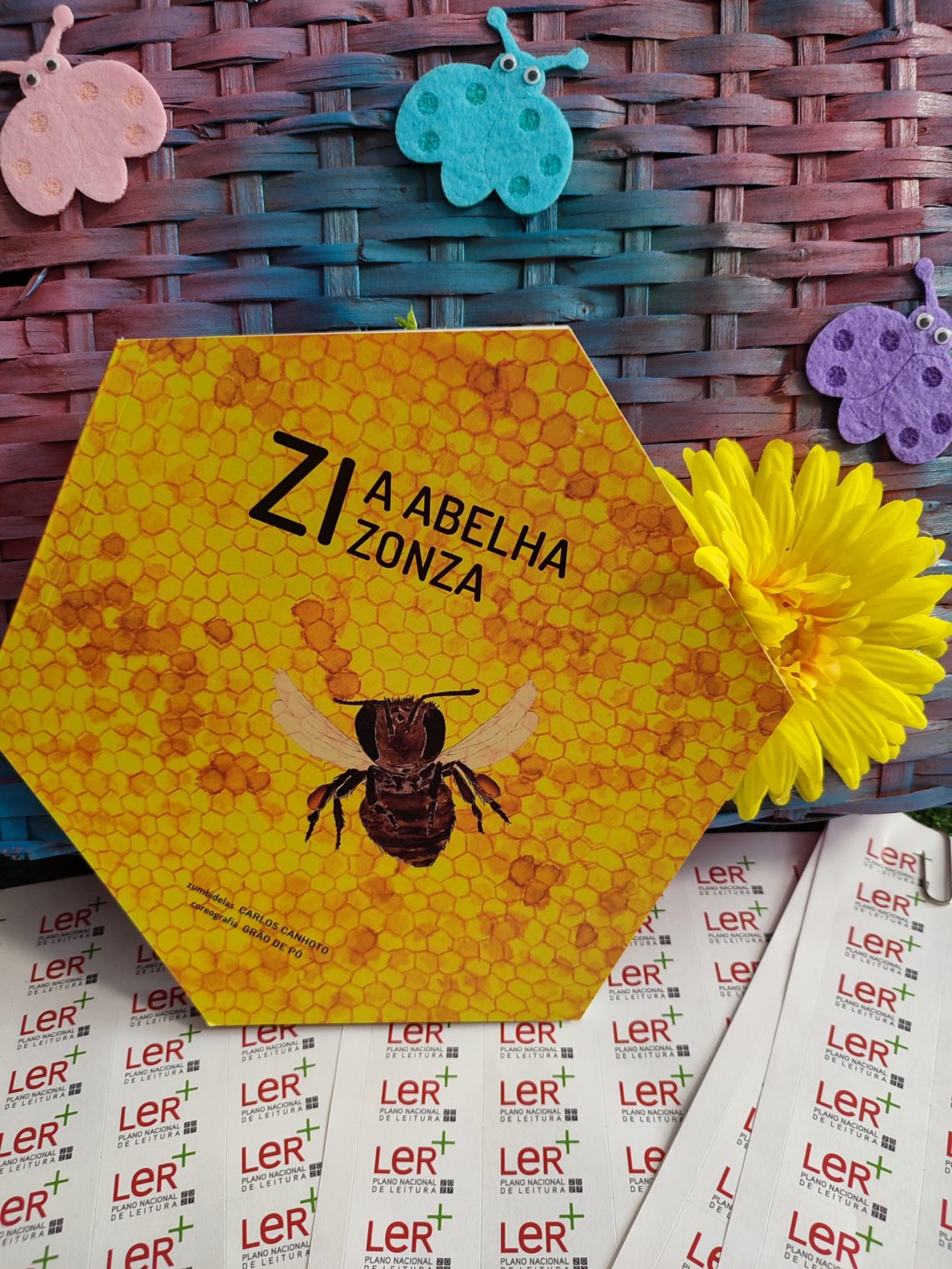 Exemplar de «Zi, a abelha zonza», livro ilustrado de Carlos Canhoto e grão de pó, com autocolantes do Plano Nacional de Leitura